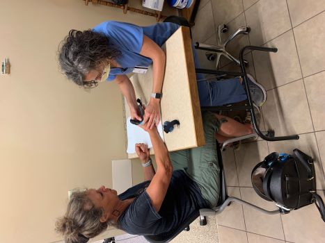 A female patient sitting at a table with Sara Hawkins, Occupational Nurse (Certified Hand Therapist). She is giving the patient upper extremity rehabilitation (hand therapy)
